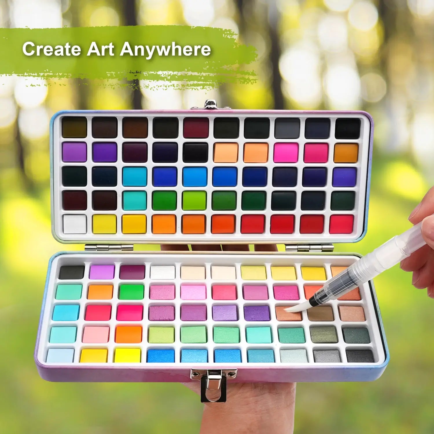 A hand holding the open 100 Colors Watercolor Paint Set outdoors, demonstrating it's the perfect portable art kit to create art anywhere.
