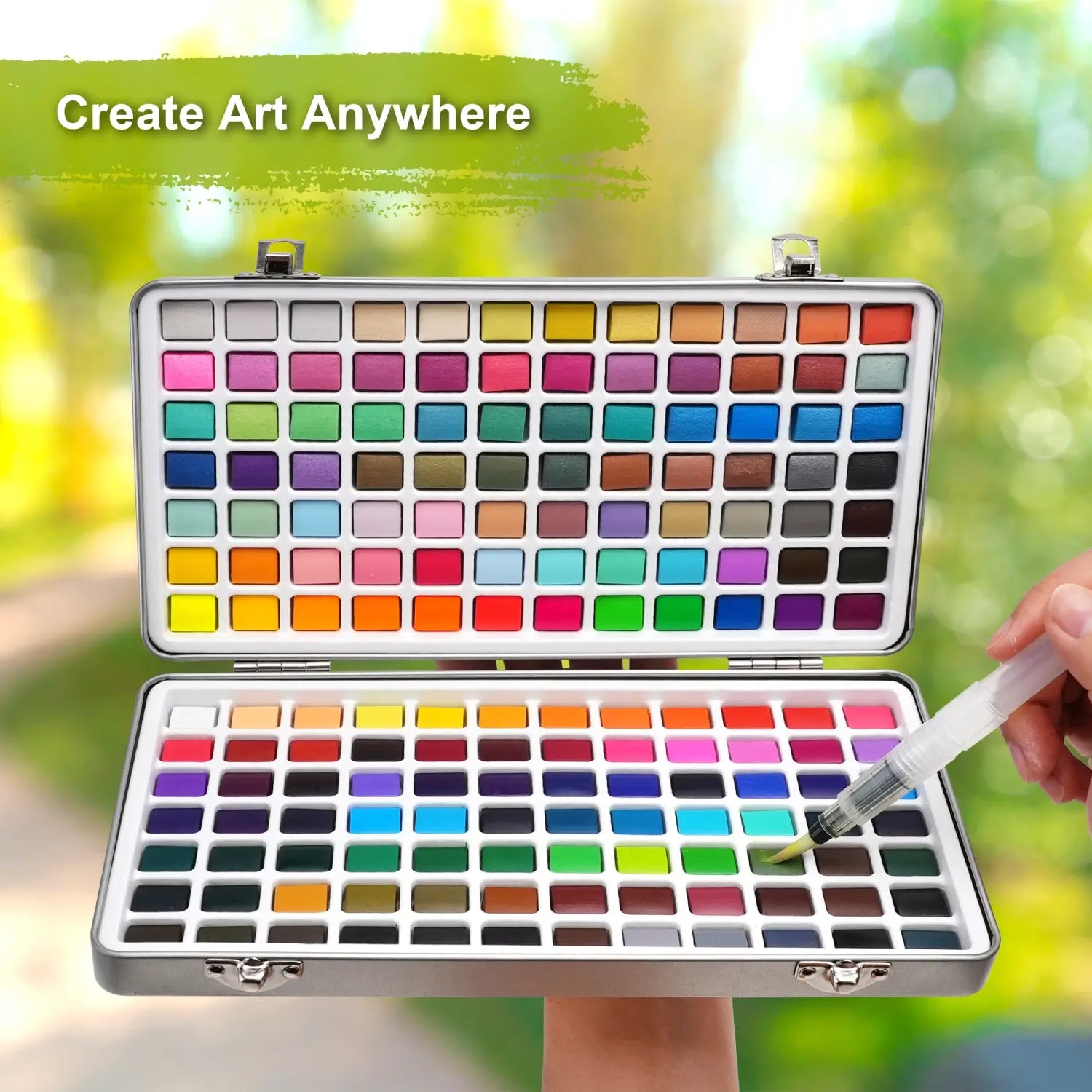The open 168 colors watercolor paint set held outdoors with a person painting, highlighting its portability to create art anywhere.