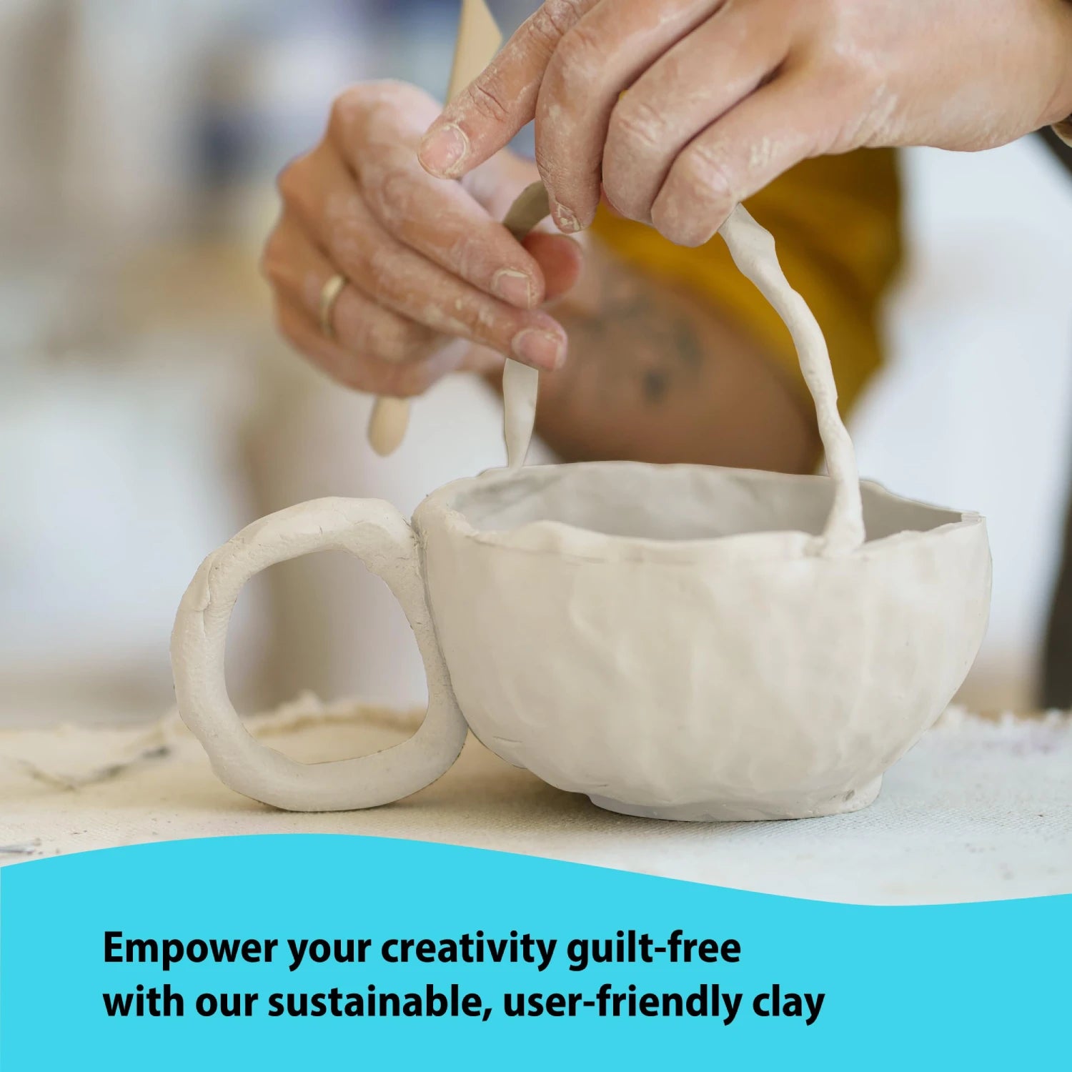 Close-up of hands attaching a handle to a cup using the sustainable and user-friendly clay from the air dry pottery kit.