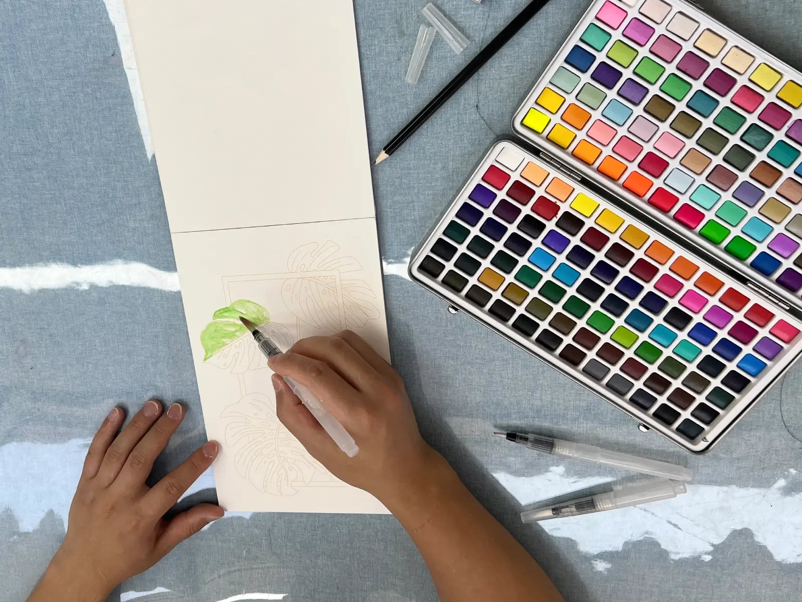 A person painting a green leaf with watercolors.